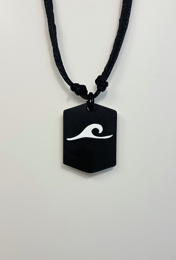 Black pendant with white wave design on a black cord against a white background